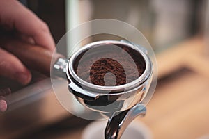 A close up portrait of a portafilter full of coffee grounds from freshly grinded coffee beans