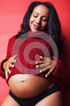 Close up portrait of pregnant woman with big belly, hands hold, red sweater on background, choise of gender, lifestyle
