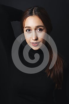 Close up portrait of pretty beautiful young woman wearing black sweater isolate over dark background