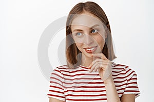 Close up portrait of pretty blond girl, teen student looking aside at promo logo, touch her face and ponder smth