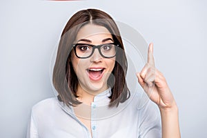 Close up portrait of pretty, charming, glad woman in shirt, eyewear finding an idea, resolution, showing index finger up with ope