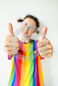 Close-up portrait of a pretty cheerful flirtatious girl in a bright striped t-shirt, LGBT flag, showing a double ok, like sign