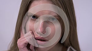 Close-up portrait of pretty confident thoughtful girl, holding hand near the face, looking seriously up, standing on