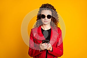 Close-up portrait of pretty focused wavy-haired girl using device posing comment isolated on bright yellow color