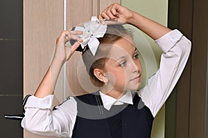 Close-up portrait of pretty girl with white bow in her hair and beautiful school uniform. First day of school.