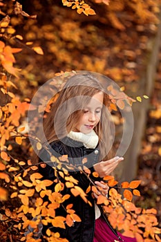 Close-up portrait of pretty little girl resting in autumnal park