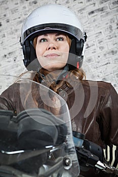 Close-up portrait of pretty motorcyclist in open helmet sitting on the motorbike