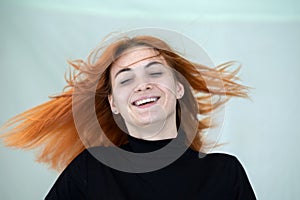 Close up portrait of pretty redhead girl with long wavy hair blowing on the wind
