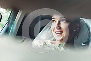 Close-up portrait of a pretty shy bride in a car window