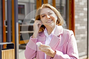 Close-up portrait of a pretty young girl wearing wireless headphones, walking around the city and listening to music