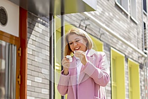 Close-up portrait of a pretty young girl wearing wireless headphones, walking around the city and listening to music outdoors