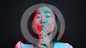 Close up portrait of professional asian woman singer performing on stage, singing into microphone and smiling to camera