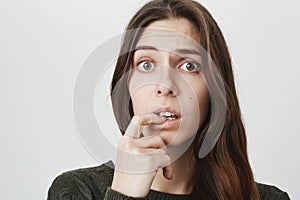 Close-up portrait of puzzled confused woman with dark long hair dressed casually, looking at camera with puzzlement