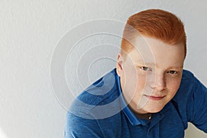 A close-up portrait of redhead guy with freckles wearing blue shirt having confident expression isolated over white background wit