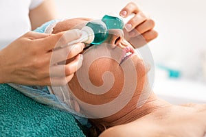 Close up portrait of relaxed senior woman  getting massage with cold blue balls