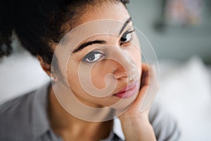 Close-up portrait of sad beautiful young woman indoors, looking at camera.
