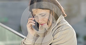 Close-up portrait of sad Caucasian brunette woman talking on the phone. Beautiful stressed businesslady having