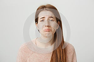 Close-up portrait of sad redhead caucasian girl with gloomy smile, whining or crying with frowned eyebrows and miserable