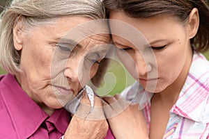 Close up portrait of sad senior woman with adult daughter