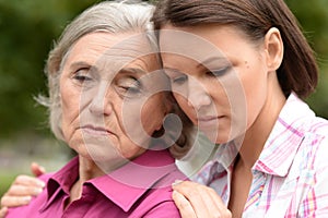 Close up portrait of sad senior woman with adult daughter