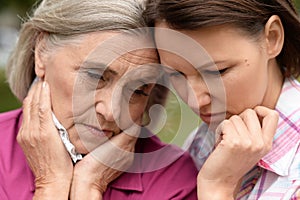 Close up portrait of sad senior woman with adult daughter