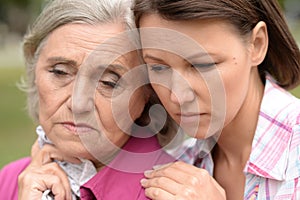 Close up portrait of sad senior woman with adult daughter