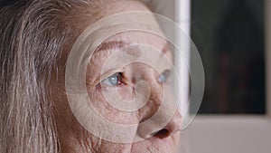 Close up portrait of sad senior woman with blue eyes gray hair and wrinkled skin