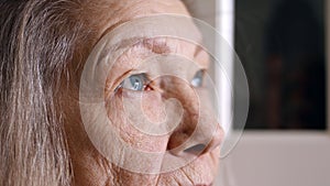 Close up portrait of sad senior woman with blue eyes gray hair and wrinkled skin