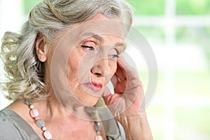 Close up portrait of sad senior woman at home