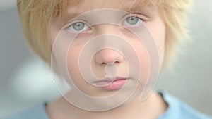 Close-up portrait of sad and thoughtful school-age child. The cute boy closed his eyes, then opened them and looks at you very ser