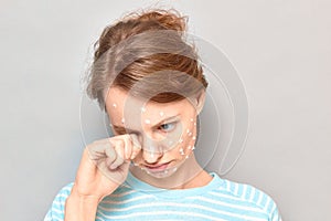 Portrait of sad tearful girl with white drops of face cream on skin