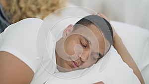 Close-up portrait of sad young handsome African American man lying in white bed looking over shoulder at unrecognizable