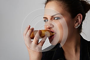 Close up portrait of a satisfied pretty young girl eating donut isolated over white background.
