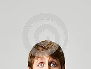 Close up portrait of school boy eyes looking on gray