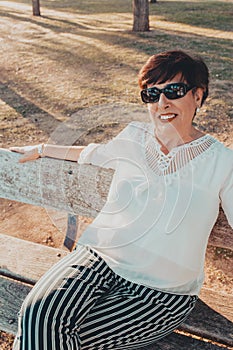 Close up portrait of a senior woman in the park sitting on a bench at sunset