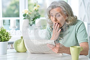 Close up portrait of senior woman reading newspaper