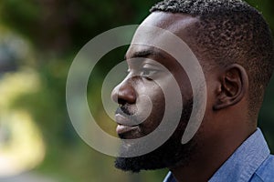 Close up portrait of serious African American man with open eyes. Handsome young calm man in blue denim shirt meditating