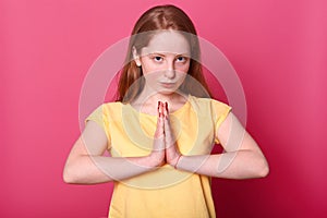 Close up portrait of serious beautiful Caucasian female posing in studio, looks directly at camera with confident expresion, keeps