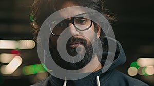 Close up portrait serious confident hipster Muslim guy Arabian man Indian bearded male at dark night city urban parking