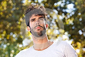 Close up serious handsome man with beard outside in nature