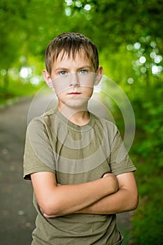 Close-up portrait of serious little boy with folded hands outdoors