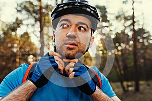 Close up portrait of serious and thoughtful cyclist close the protective helmet outdoors and looking away, thinking about the