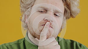 Close-up portrait of serious and worried guy thinking rubbing chin contemplating on problem on yellow background