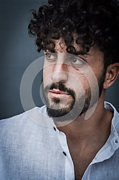 Close up portrait of a serious young man with a beard and curly hair