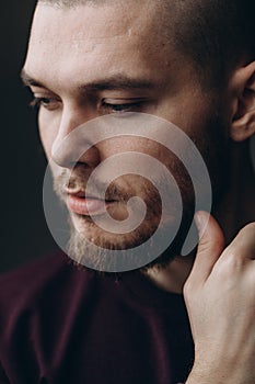 Close-up portrait of a serious young man looking away on a gray background. bald with a beard