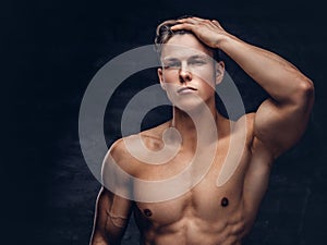 Close-up portrait of a shirtless young man model with a muscular body and stylish haircut posing at a studio