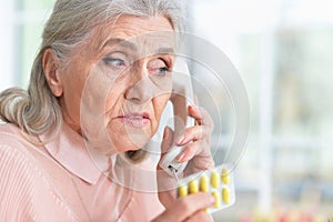 Close up portrait of sick senior woman calling to doctor