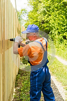 Close up portrait of skilled handyman mounting wooden board fence