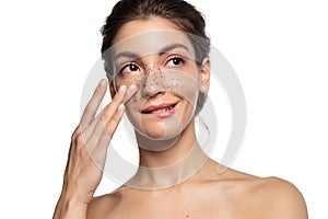 Smiling woman applying cosmetic facial skin scrub