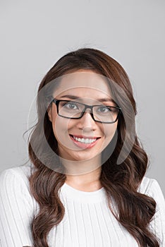 Close-up portrait of smiling confident businesswoman looking straight, isolated on grey background.